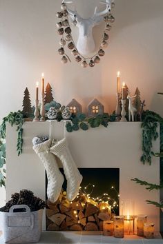 christmas decorations are displayed in front of a fireplace with candles and stockings on the mantel