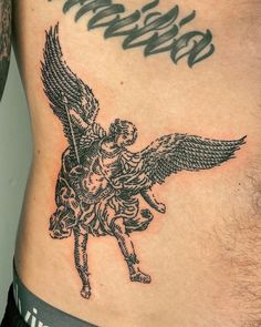 an angel tattoo on the side of a man's lower back, with words above it