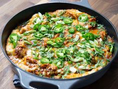 an omelet with green peppers and onions in a skillet on a wooden table