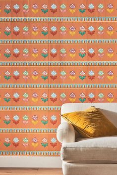 a white couch sitting in front of a wallpapered wall with flowers on it