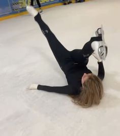 a female figure skating on an ice rink with her arms in the air and legs out