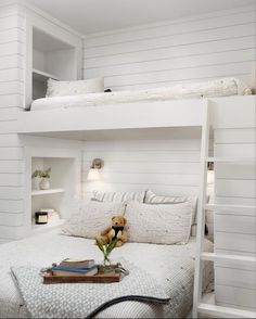 there is a white bunk bed in the room with books and flowers on the table