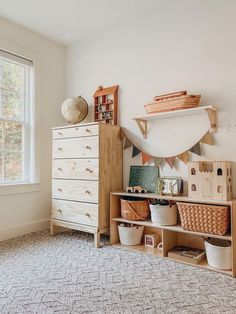 a white dresser sitting next to a window filled with baskets and other items on top of it