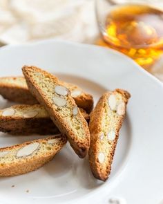 several pieces of bread on a white plate with a glass of tea in the background