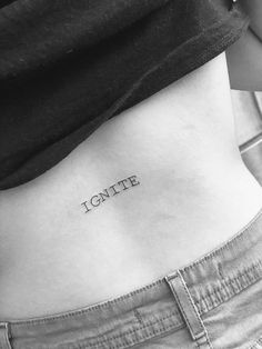 a woman's stomach with the word ignite tattooed on her left side ribcage