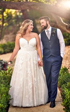 a bride and groom holding hands walking down a path