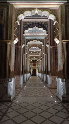 the inside of a building with columns, arches and ceiling lights on either side of it