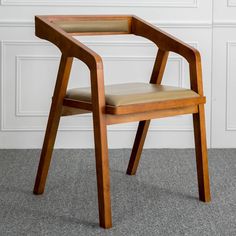 a wooden chair sitting on top of a carpeted floor next to a white wall