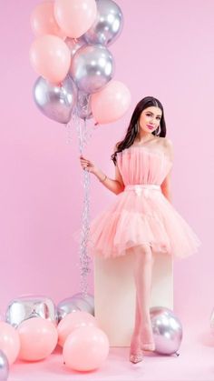 a woman in a pink dress holding balloons