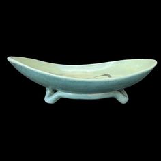 a white ceramic bowl sitting on top of a wooden stand in the shape of a boat