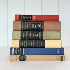 five books stacked on top of each other in different colors and sizes, sitting next to each other