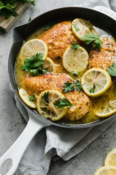 chicken with lemons and cilantro in a skillet on a gray surface