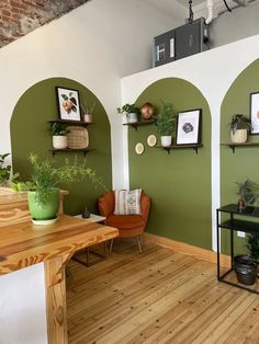 a room with green walls and wooden flooring, potted plants on the wall