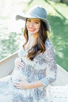 a pregnant woman in a hat smiles while sitting on a boat