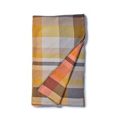 an orange and brown plaid blanket folded on top of a white surface