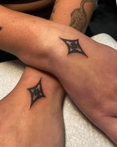 two people with matching tattoos on their legs sitting next to each other, both holding hands