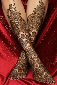 the legs and feet of a woman with henna tattoos on their arms, both covered in