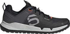 the five ten running shoe is black and grey with orange accents on the upper part of the shoe