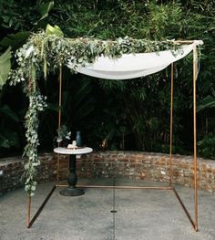 an outdoor ceremony setup with greenery and white draping