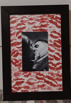 a black and white photo with red lipstick on it, framed in a wooden frame