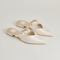 a pair of white shoes with pearls on them