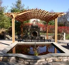 an outdoor patio with a fire pit and pergolated gazebo in the background