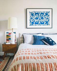 a bedroom with a bed, lamp and pictures on the wall