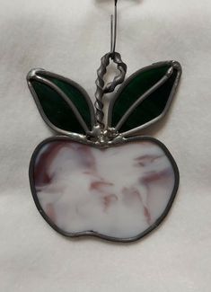 an apple shaped glass ornament hanging from a hook