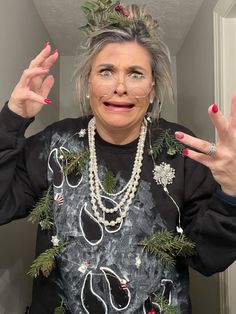 an older woman with grey hair and christmas decorations on her head is making the peace sign