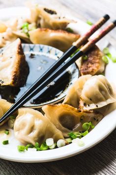 a white plate topped with dumplings and chopsticks