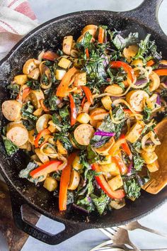 a skillet filled with stir fry vegetables on top of a wooden spatula next to utensils