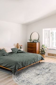 a bedroom with a bed, dresser and rug in it's centerpieces