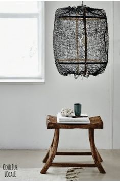 a wooden table with a book and cup on it next to a light fixture hanging from the ceiling