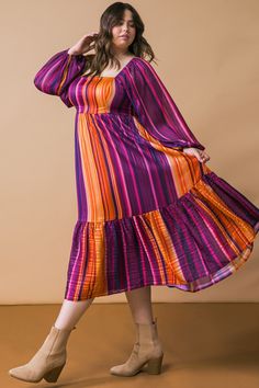 a woman in a purple and orange striped dress poses with her hands on her hips