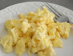 scrambled eggs on a white plate with a fork