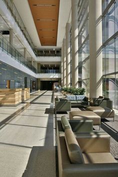 an empty lobby with couches and tables in the foreground, windows on both sides