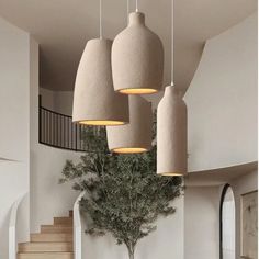 three lamps hanging from the ceiling above a dining room table with chairs and vases