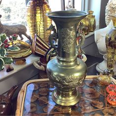 an ornate vase sitting on top of a glass table next to other decorative items in front of a window