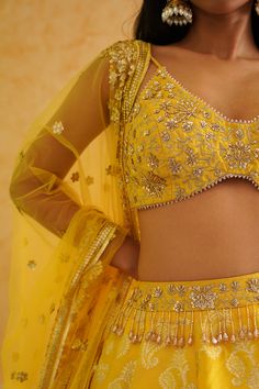 Yellow Brocade Lehenga Set | Deepika Chadha Deepika Chadha's stunning yellow brocade fabric lehenga, beautifully adorned with intricate gold crystal, sequins and bead embroidered blouse. The yellow color adds a touch of glamour and sophistication to your look, while its texture ensures you feel comfortable all day or night long. It is styled with a yellow net Dupatta to complete the look. Included in Purchase: Lehenga, Blouse & Dupatta Set Product Specification Color: Yellow Fabric: Brocade, Net Neckline: Spaghetti Strap Occasion: Bridal, Engagement, Formal Event Designer: Deepika Chadha Work: Hand Embroidery Gold Beads Sequins, Stones, Cutdana, Crystals Care Instructions: Dry Cleaning only, No Flat Ironing on Hand Embroidery *Jewelry sold separatelyCustomization options:Can be customized Yellow Kundan Sharara With Intricate Embroidery, Yellow Kundan Set With Intricate Embroidery, Embellished Yellow Sets For Diwali, Embellished Yellow Set For Diwali, Diwali Embellished Yellow Sets, Festive Yellow Anarkali Set With Intricate Embroidery, Festive Yellow Embellished Anarkali Set, Festive Yellow Embellished Dupatta, Yellow Anarkali Set With Mirror Work