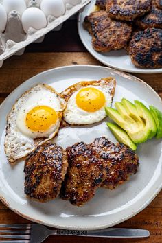 an egg, meat and avocado are on a plate next to some eggs