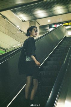 a woman standing on an escalator with her luggage