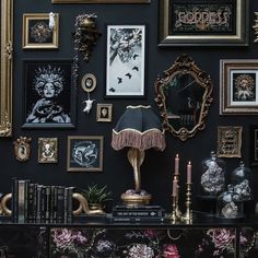 a black wall covered in pictures and other items with a cat sitting on top of it