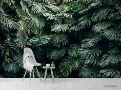 a white chair sitting in front of a lush green plant wallpapered with leaves