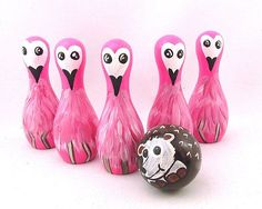 five pink flamingos are lined up next to an easter egg with one painted like a sheep