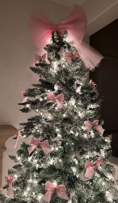 a white christmas tree with pink bows and lights