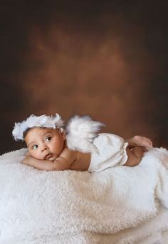 a baby with angel wings laying on a blanket