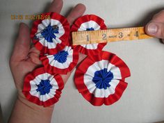 someone is measuring the size of three red, white and blue flower hair clips on their fingers