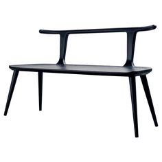 a black bench sitting on top of a white floor next to a wooden shelf with two legs