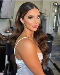 a woman with long brown hair wearing a white top