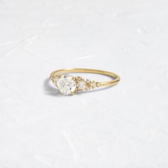 a gold ring with three pear shaped diamonds on the side, sitting on a white surface